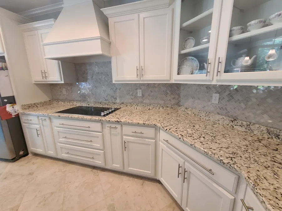 White shaker kitchen remodel with granite counters, custom vent hood and marble tile backsplash