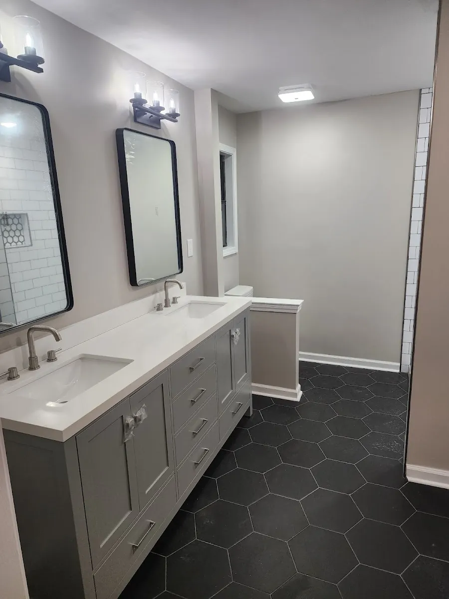 Master bathroom remodel with double vanity, framed mirrors and black hexagon tile floor