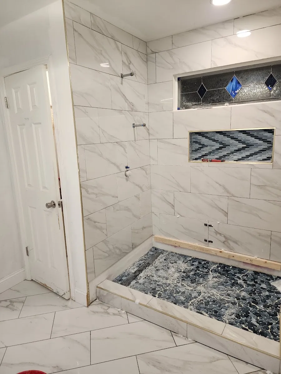 Marble tile walk-in shower with built-in niche and mosaic pebble shower floor