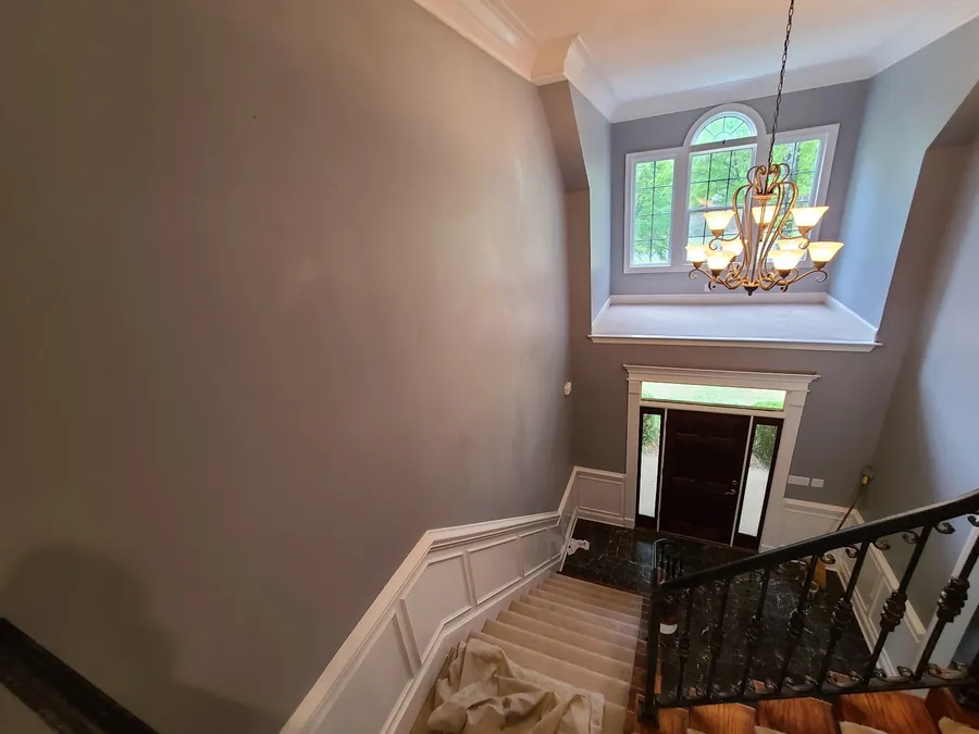 Two-story foyer repaint with wainscot, chandelier and wrought iron stair balusters