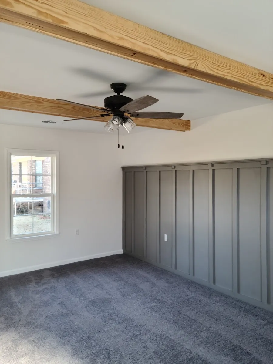 Board-and-batten accent wall with exposed wood ceiling beam and new ceiling fan