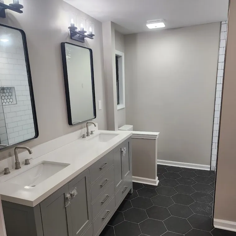 Master bathroom with double vanity, framed mirrors and black hexagon tile floor