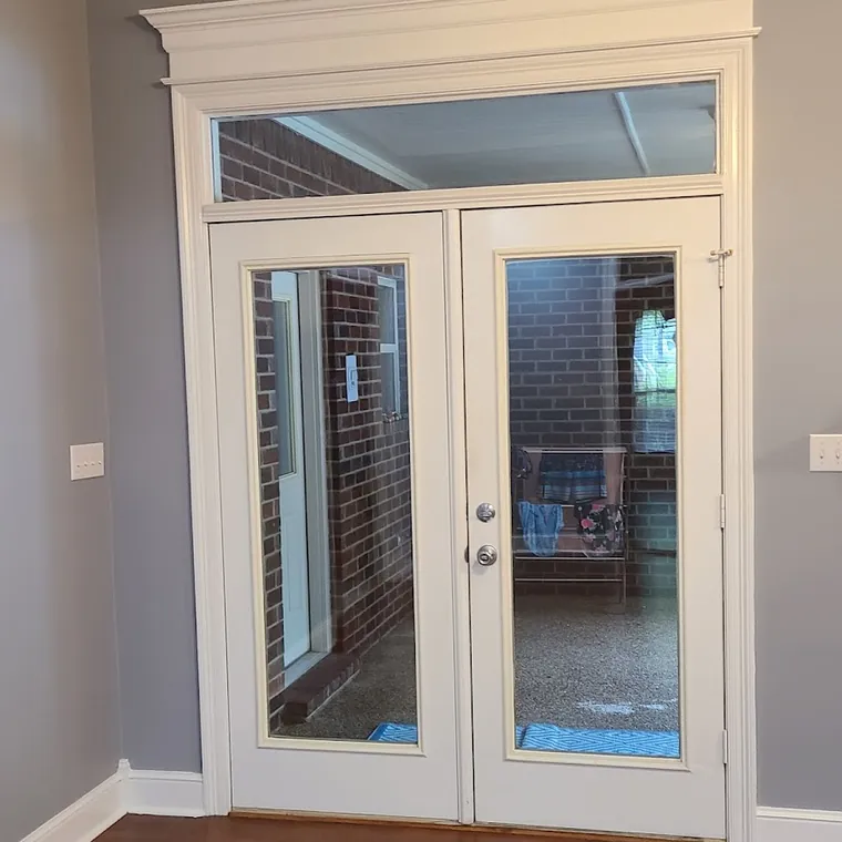 Interior French doors with a transom window and refinished hardwood flooring