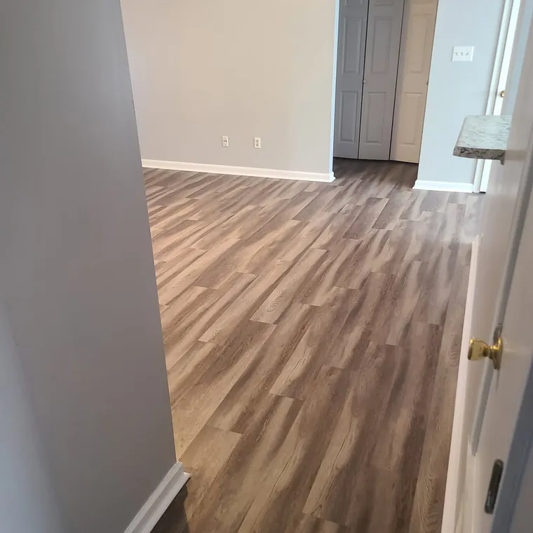 Luxury vinyl plank flooring installed in a freshly painted room with new baseboards
