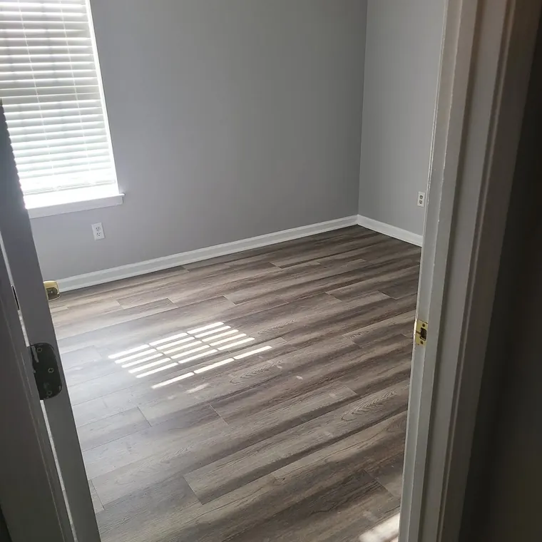 New wood-look flooring and baseboards in a renovated bedroom