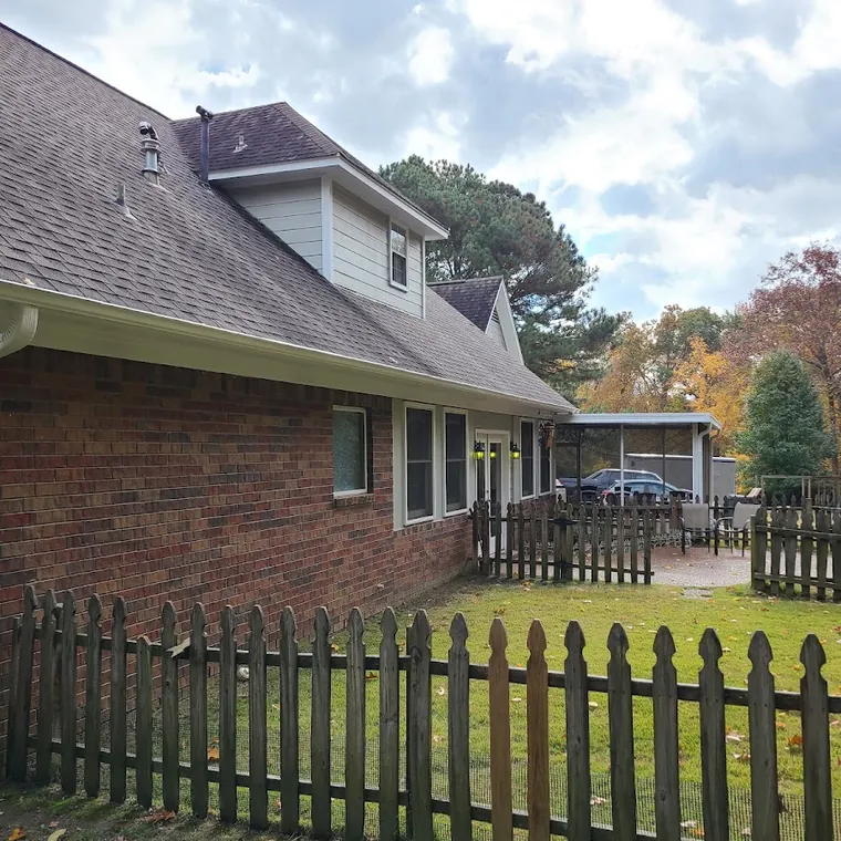 Wood picket fence and landscaping in front of a brick home