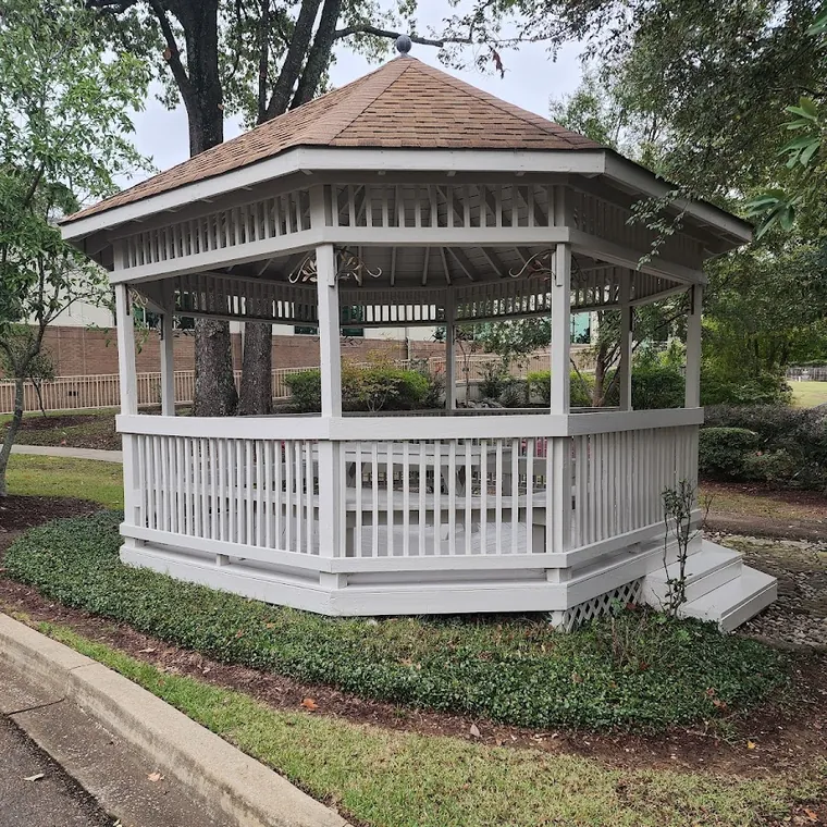 Custom built white gazebo with railings in a residential yard