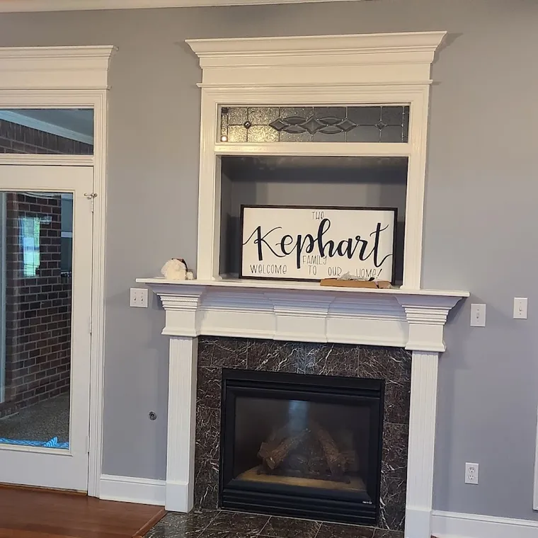 Fireplace surround and painted mantel with new trim in a remodeled living room