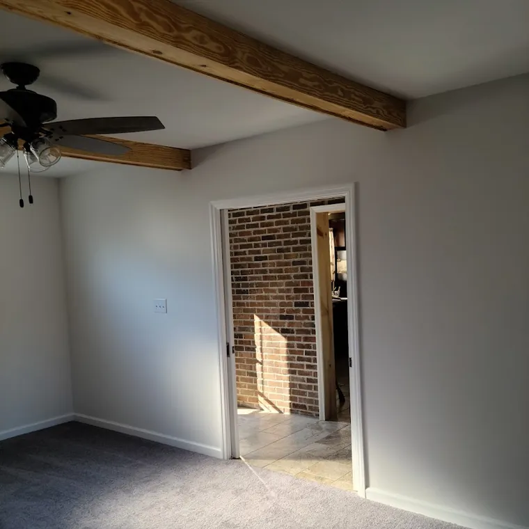 Bedroom with a navy accent wall, new trim and refinished ceiling after renovation