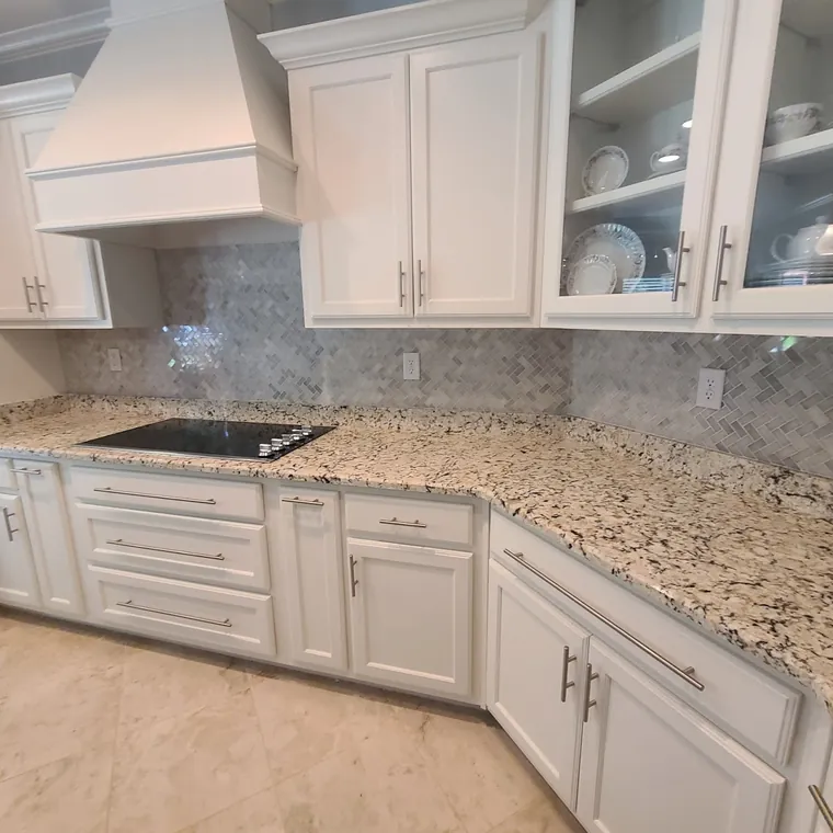 White shaker kitchen remodel with granite countertops, custom vent hood and marble tile backsplash
