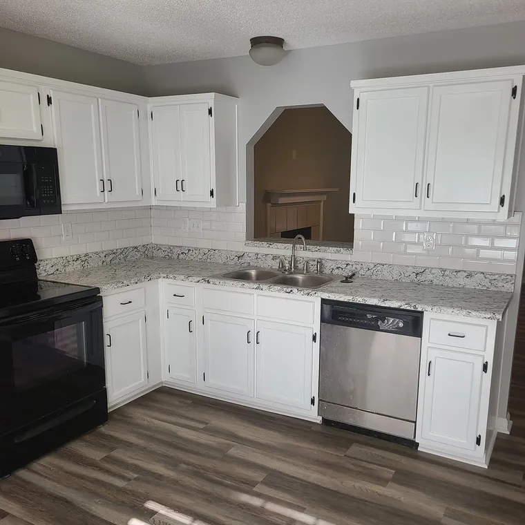 Remodeled kitchen with white cabinets, granite counters, stainless appliances and vinyl plank flooring