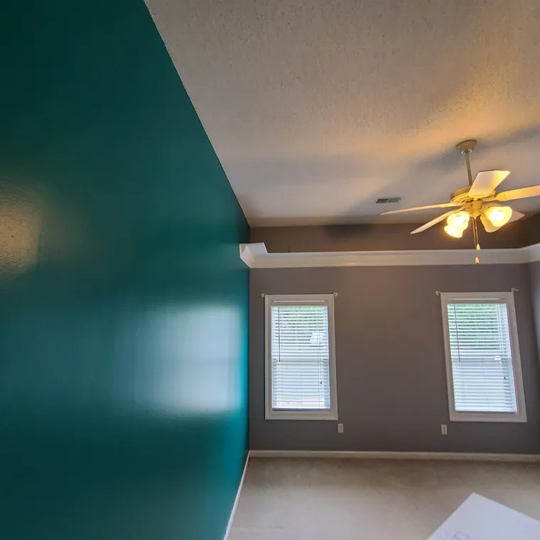 Bedroom painted in a deep teal with a new ceiling fan and crisp trim lines