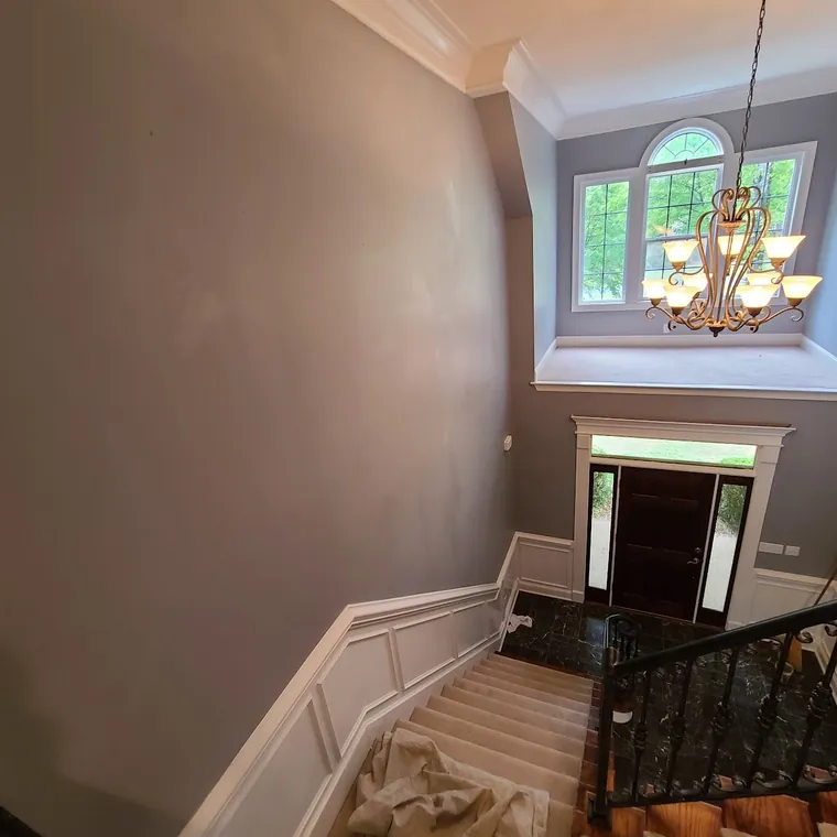 Two-story foyer painted with wainscot and wrought iron stair balusters