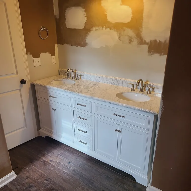 Bathroom vanity wall mid-repaint with patched and primed drywall